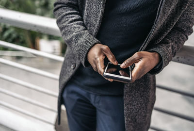 Midsection of man using mobile phone