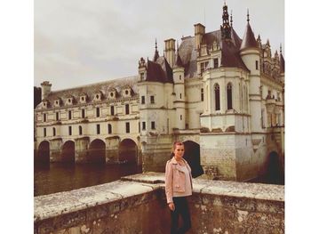 Woman standing by historic building against sky