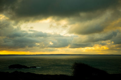 Scenic view of sea against dramatic sky during sunset