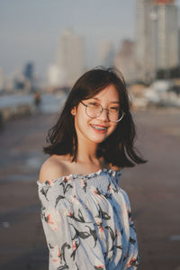 Portrait of smiling young woman standing in city