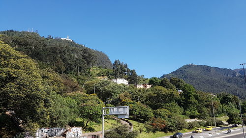 Trees and mountains against clear blue sky