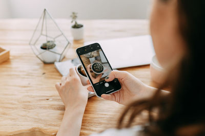 A young woman takes photos of objects goods things using a mobile phone creates content for a blog