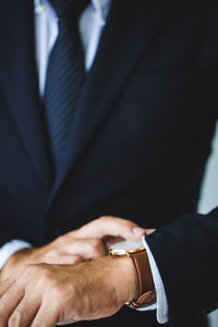 Midsection of businessman checking time in office