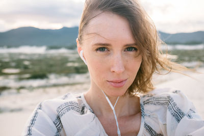 Close-up portrait of smiling young woman against sky