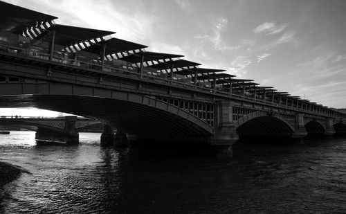 Bridge over river against cloudy sky