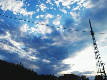 Low angle view of electricity pylon against cloudy sky