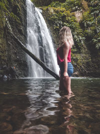 Full length of woman standing against waterfall