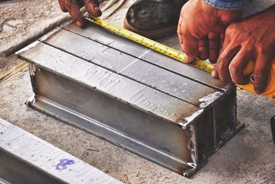 Cropped hands manual workers measuring metal at workshop