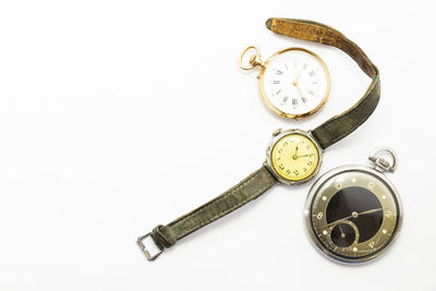 High angle view of pocket watches and wristwatch against white background