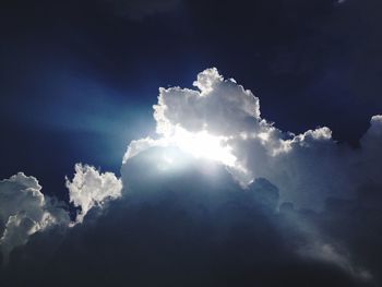 Low angle view of sun shining through clouds