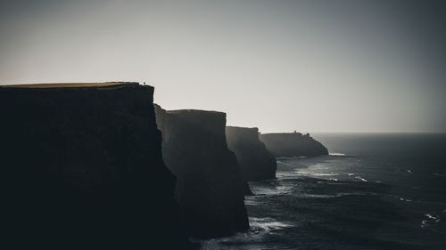 Rock formation on sea against clear sky