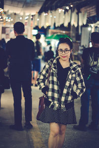 Portrait of young woman in city at night