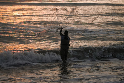 Rear view of silhouette man standing in sea