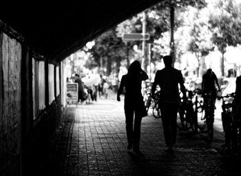 Rear view of silhouette people walking on sidewalk in city
