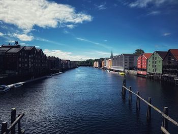 Buildings by river against sky