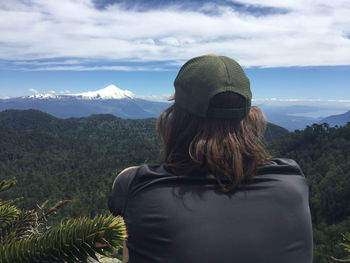 Rear view of person looking at mountains against sky