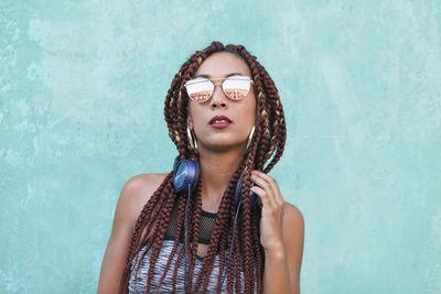 Portrait of woman with long braided hair standing against wall