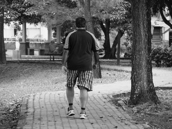 Rear view of woman walking on zebra crossing in city