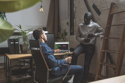 Businessmen with beer bottle talking at workplace