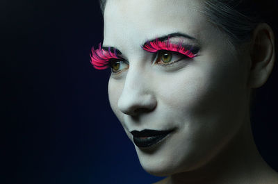 Close-up of smiling beautiful woman against black background