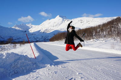 Full length of woman jumping on snow covered landscape