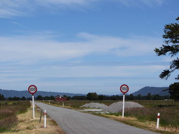 Signs along road against blue sky