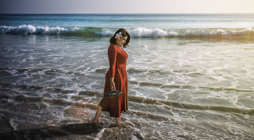 Woman standing at beach against sky