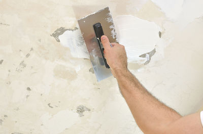 Applying spackle compound with a finishing trowel to a ceiling