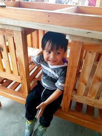 High angle view of cute boy sitting on wood