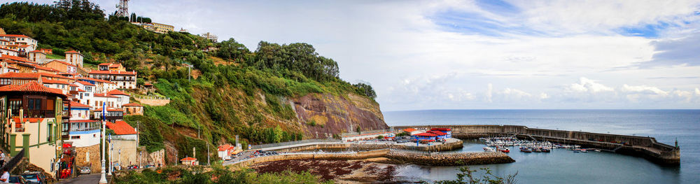 Panoramic houses by sea against sky