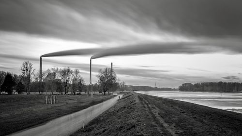 Road by agricultural field against storm clouds