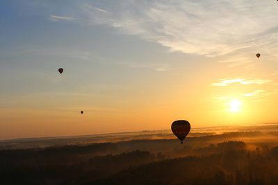 Hot air balloon flying over landscape against sky during sunset