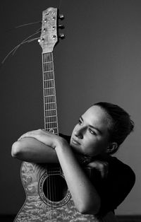 Thoughtful young woman with guitar at home