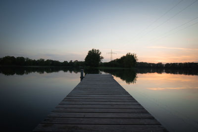 Pier over lake against sky during sunset