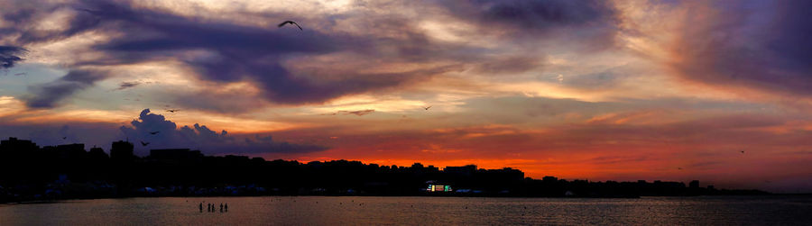 Silhouette of buildings against cloudy sky during sunset
