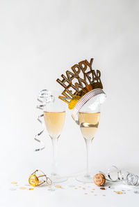 Glasses of champagne and happy new year hat on white background.