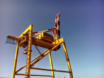 Low angle view of crane against clear blue sky