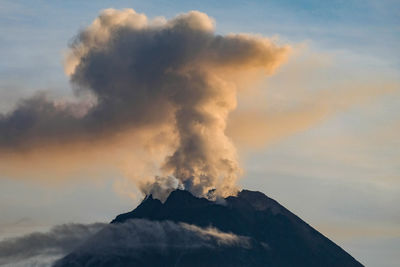 Smoke emitting from volcanic mountain against sky during sunset