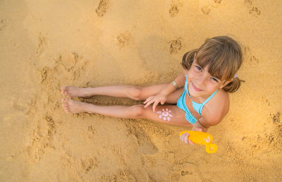 Directly above shot of girl with suntan lotion at beach
