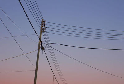 Low angle view of electricity pylon against clear blue sky