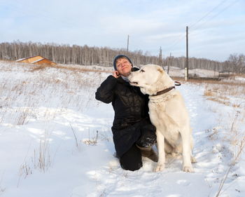 A woman sitting with a shepherd on a winter rural road against the backdrop of the village.