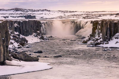 Scenic view of waterfall against sky during winter