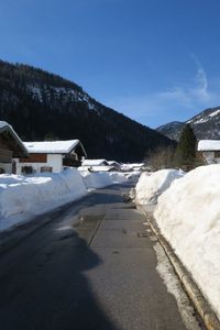 Snow covered houses by mountain against sky