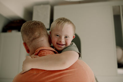 Portrait of boy with down syndrome hugging father at home