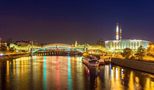 Illuminated bridge over river against sky at night