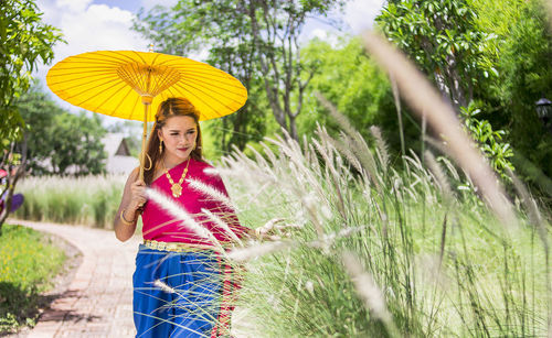 Portrait of woman standing by plants on field