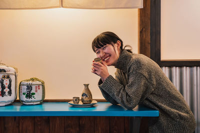 Portrait of smiling young woman sitting on table