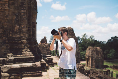 Mid adult man photographing with digital camera at ankor wat temple