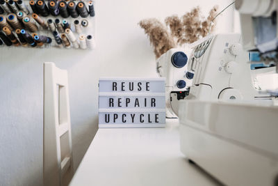 Reuse, repair, upcycle text on light board on sewing machines background. stack of old jeans, denim