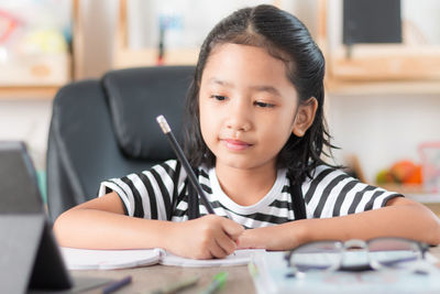 Girl writing on book at table